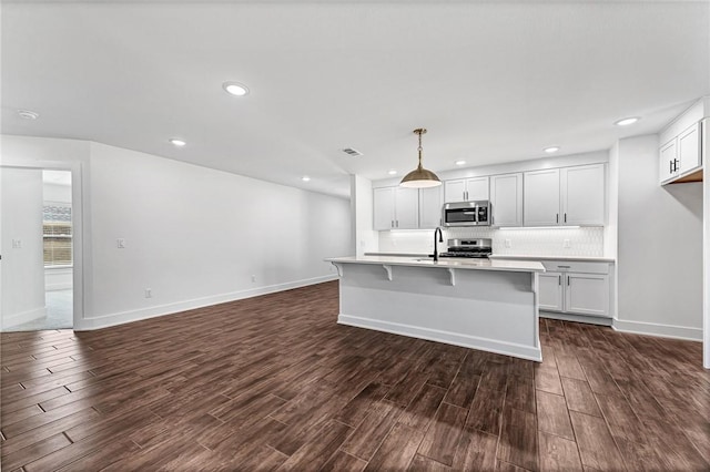 kitchen with light countertops, backsplash, dark wood-style floors, and appliances with stainless steel finishes