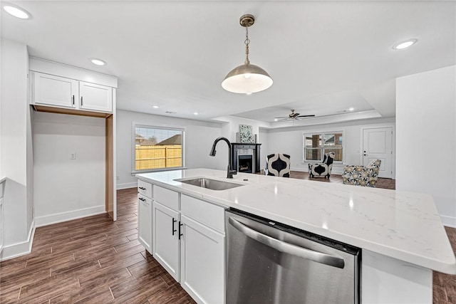 kitchen featuring wood tiled floor, a fireplace, a sink, white cabinets, and dishwasher