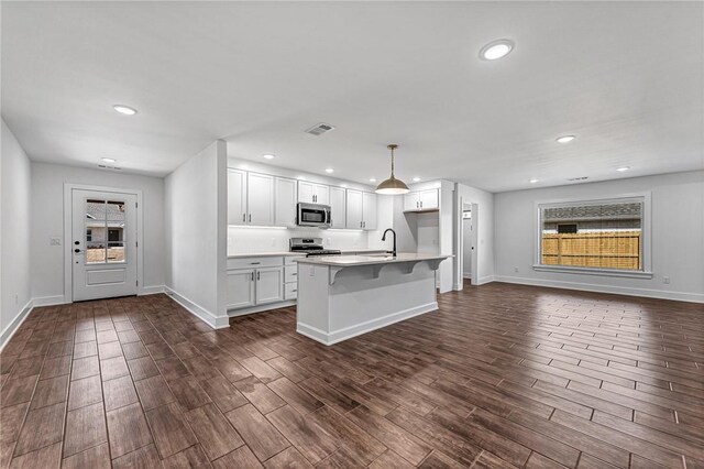 kitchen with visible vents, dark wood-type flooring, open floor plan, stainless steel appliances, and white cabinets