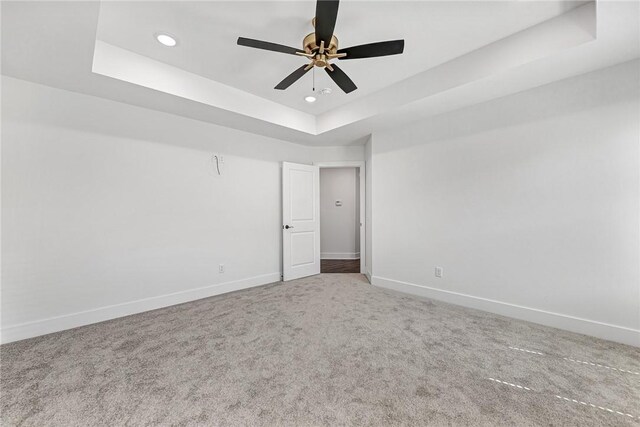 carpeted empty room featuring recessed lighting, a tray ceiling, baseboards, and ceiling fan
