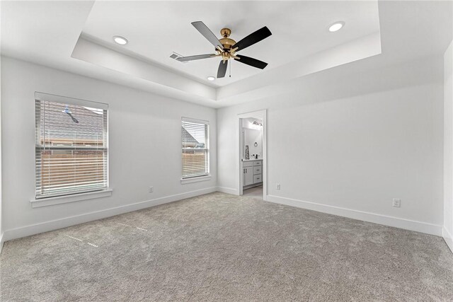 unfurnished bedroom with a tray ceiling, baseboards, and light colored carpet