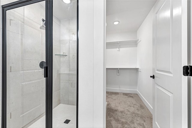 bathroom with a stall shower, a walk in closet, and baseboards