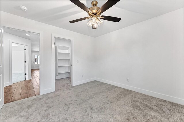 unfurnished bedroom with a walk in closet, ceiling fan, baseboards, carpet floors, and a closet
