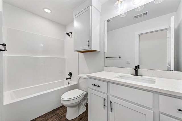 bathroom featuring visible vents, toilet, wood finished floors, shower / bath combination, and vanity