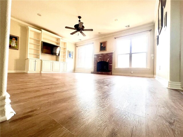 unfurnished living room with light wood-type flooring, a fireplace, plenty of natural light, and built in shelves