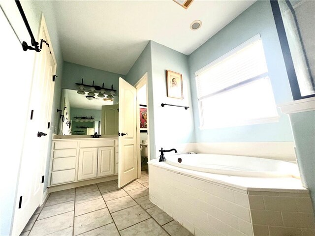 bathroom featuring tile patterned flooring, vanity, and a relaxing tiled tub