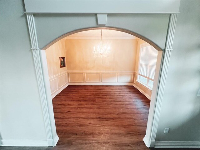 empty room with an inviting chandelier, crown molding, and hardwood / wood-style floors