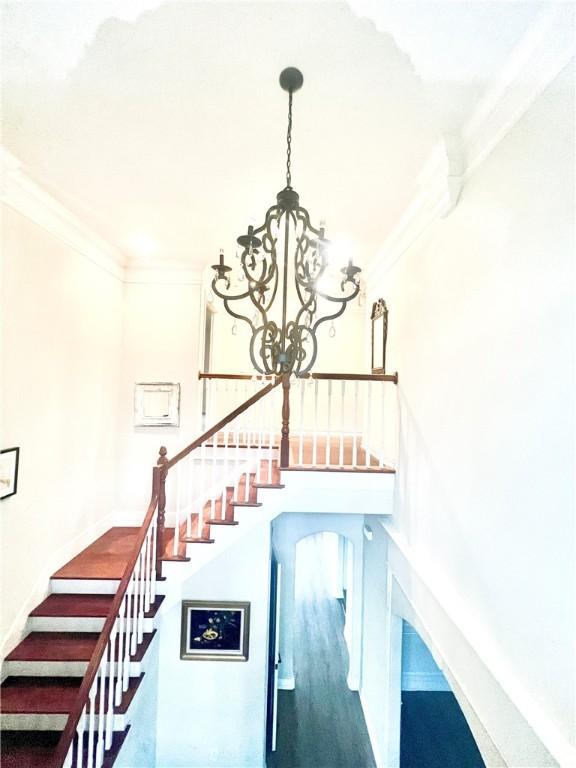 stairway featuring ornamental molding and an inviting chandelier