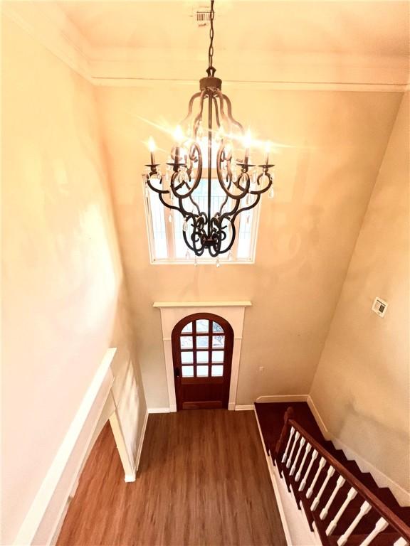 entryway with a chandelier, ornamental molding, and hardwood / wood-style flooring