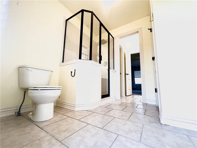 bathroom featuring tile patterned flooring, a shower with shower door, and toilet