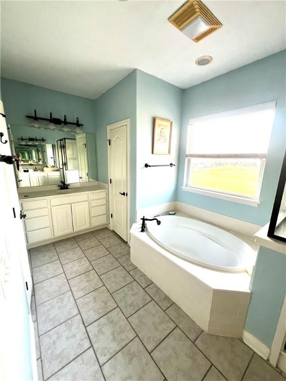 bathroom featuring tile patterned flooring, tiled tub, and vanity