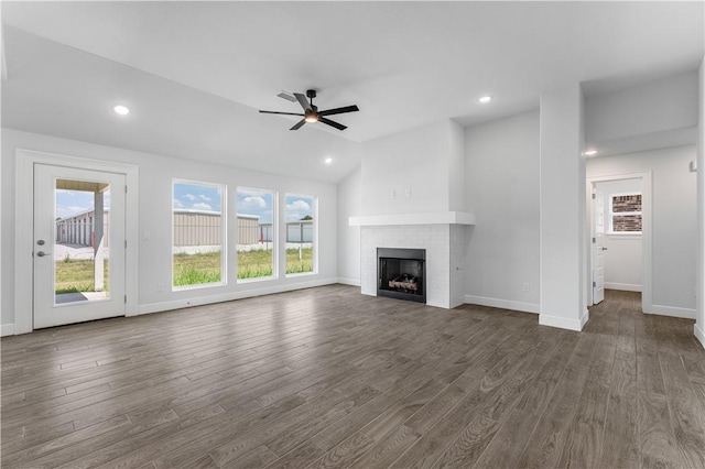 unfurnished living room featuring vaulted ceiling, ceiling fan, dark wood-type flooring, and a brick fireplace