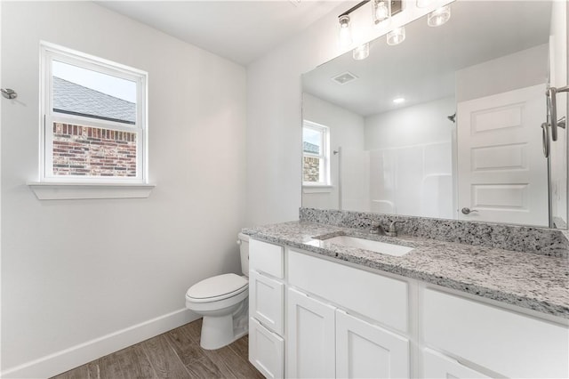 bathroom with baseboards, toilet, wood finished floors, walk in shower, and vanity