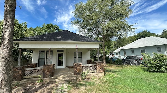 rear view of house featuring a lawn and covered porch