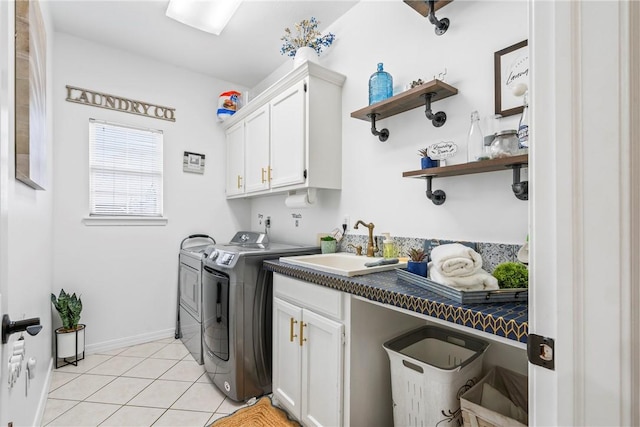 laundry area featuring cabinets, light tile patterned floors, sink, and washing machine and clothes dryer