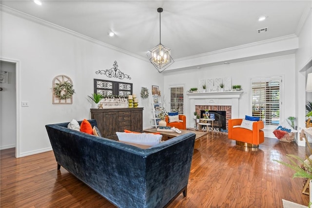 living room featuring a chandelier, wood-type flooring, ornamental molding, and a fireplace