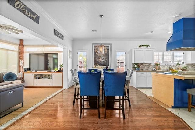 dining room with ornamental molding and light hardwood / wood-style flooring