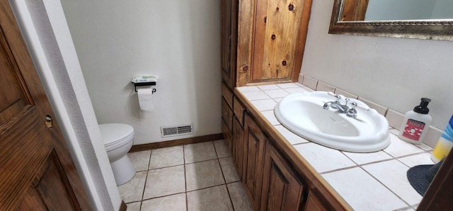 bathroom featuring vanity, baseboards, tile patterned flooring, toilet, and visible vents