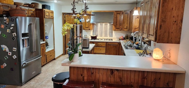 kitchen with hanging light fixtures, appliances with stainless steel finishes, exhaust hood, light tile patterned floors, and kitchen peninsula