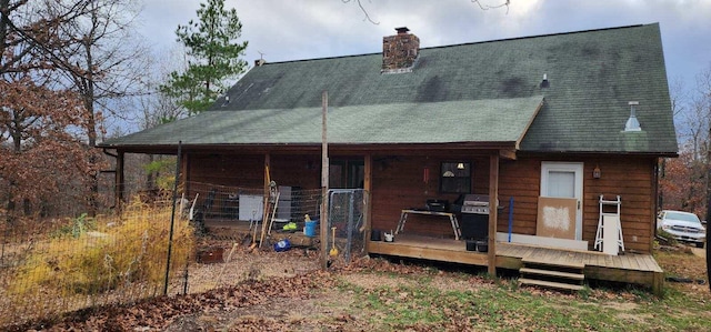 rear view of house with roof with shingles and a chimney