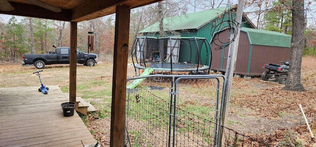 view of yard featuring a trampoline, a storage shed, a gate, and an outbuilding
