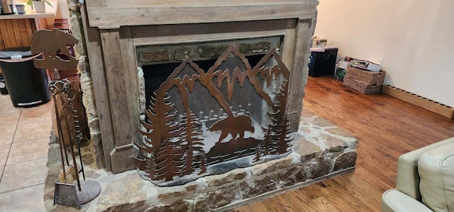 interior details featuring a fireplace, a baseboard heating unit, baseboards, and wood finished floors