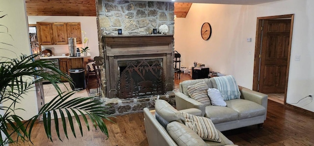 living area with wood ceiling, wood finished floors, and a fireplace with raised hearth