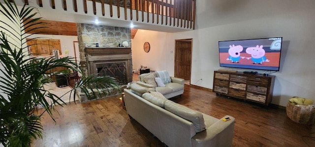 living room featuring a fireplace with raised hearth, a towering ceiling, and wood finished floors