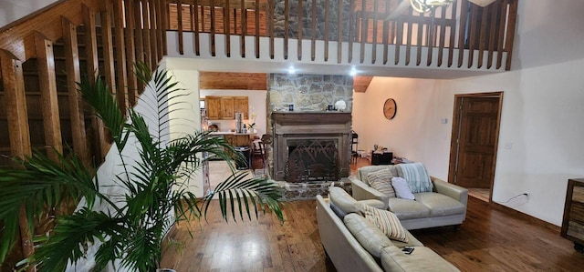 living room featuring dark hardwood / wood-style flooring, a stone fireplace, and a towering ceiling