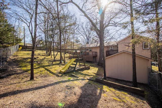 view of yard featuring a wooden deck, a storage shed, and a playground