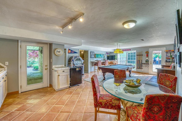 dining room featuring a textured ceiling, rail lighting, a wealth of natural light, and billiards