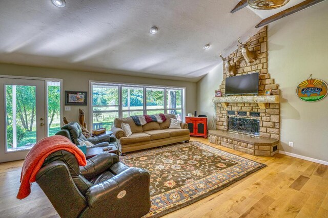 3128 Silver Valley Rd, Harrison, AR 72601 - living room with vaulted ceiling, wood finished floors, a stone fireplace, and baseboards