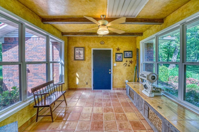 sunroom / solarium with beam ceiling, a wealth of natural light, and ceiling fan