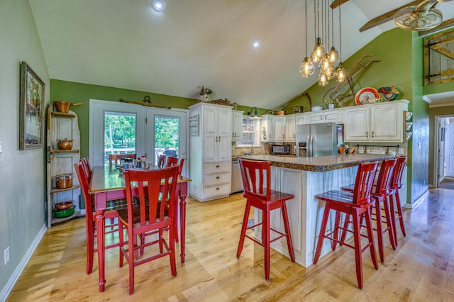 kitchen featuring a breakfast bar, a center island, hanging light fixtures, white cabinetry, and stainless steel fridge with ice dispenser