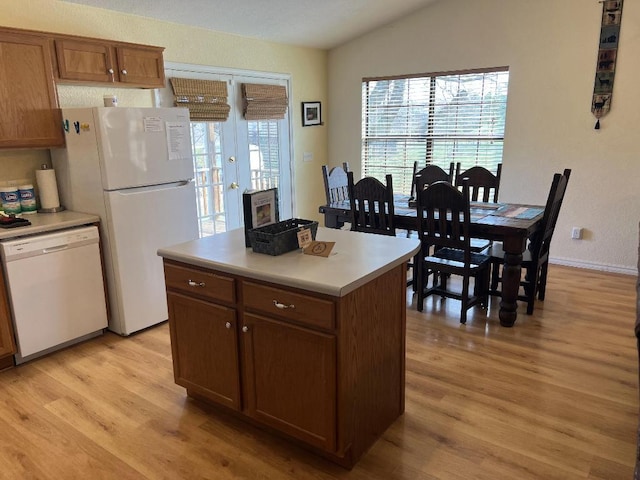 kitchen featuring light hardwood / wood-style floors, white appliances, vaulted ceiling, and a kitchen island