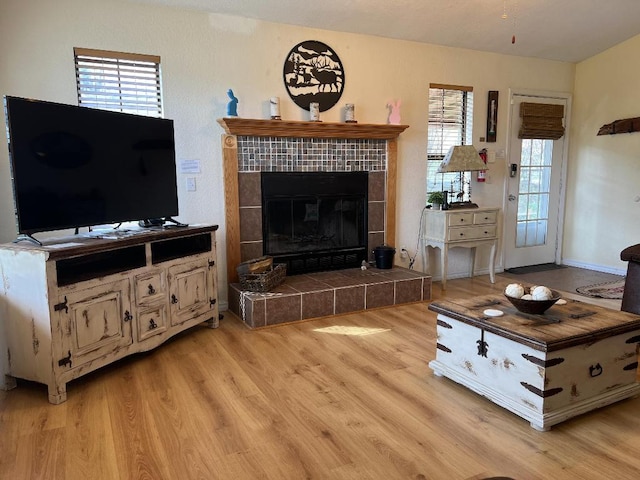 living room with light hardwood / wood-style flooring and a tiled fireplace