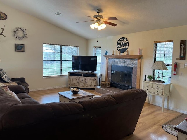 living room with wood-type flooring, lofted ceiling, ceiling fan, and a fireplace