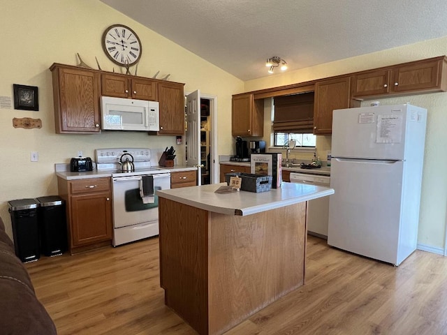 kitchen featuring light wood-type flooring, vaulted ceiling, white appliances, and a center island