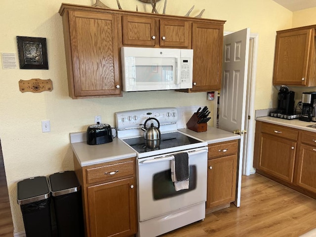 kitchen with white appliances and light hardwood / wood-style floors