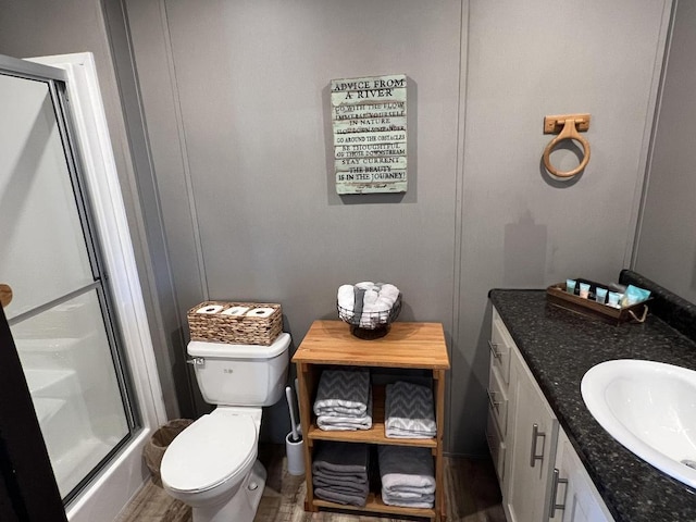 bathroom with walk in shower, vanity, and toilet