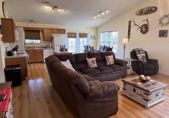 living room featuring light wood-type flooring, rail lighting, and lofted ceiling