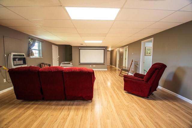 home theater room with light hardwood / wood-style floors, heating unit, and a paneled ceiling