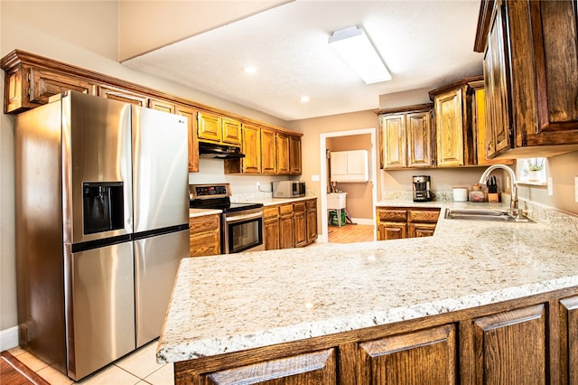 kitchen featuring light stone counters, light wood-type flooring, appliances with stainless steel finishes, sink, and kitchen peninsula