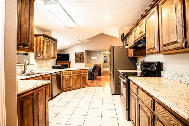 kitchen with stainless steel appliances, light tile patterned flooring, sink, lofted ceiling with skylight, and ceiling fan