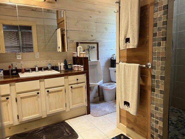 bathroom with tiled shower, wood walls, vanity, toilet, and tile patterned floors