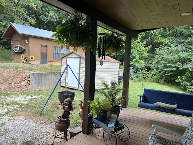 wooden terrace with a storage shed and a lawn