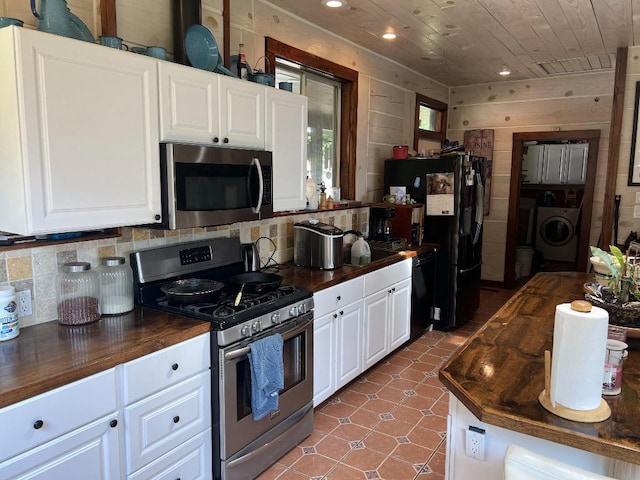 kitchen with washer / clothes dryer, white cabinets, wood walls, butcher block countertops, and black appliances