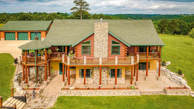 rear view of property featuring a chimney, a shingled roof, concrete driveway, log exterior, and stone siding