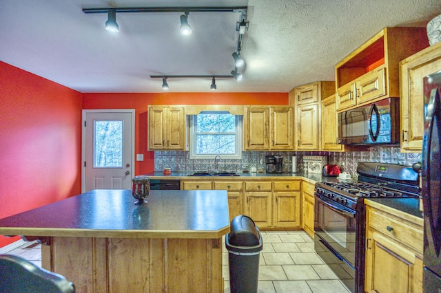 kitchen featuring sink, tasteful backsplash, a kitchen island, and black appliances