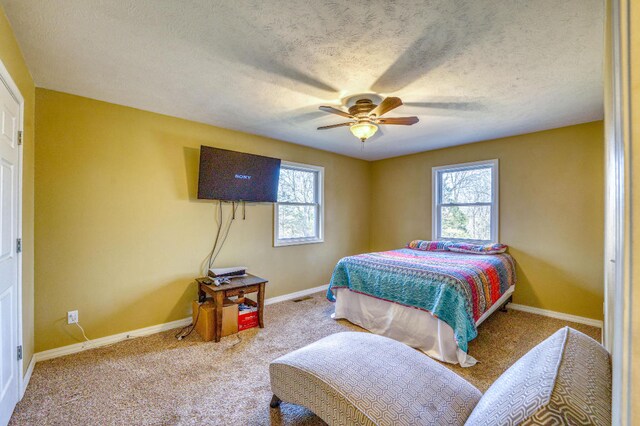 bedroom featuring multiple windows, a textured ceiling, carpet floors, and ceiling fan